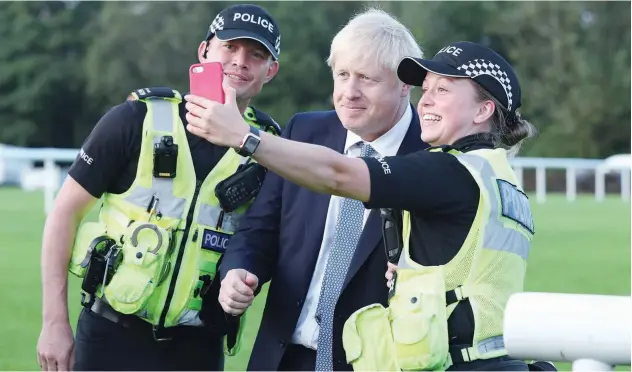  ?? Agence France-presse ?? Boris Johnson has a selfie taken with police officers at Whaley Bridge Football Club in Derbyshire.