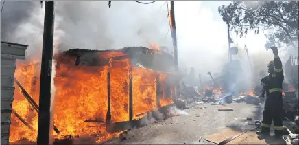  ?? PICTURE: AYANDA NDAMANE ?? A fire at the Imizamo Yetho formal settlement near Hout Bay claimed several lives. Residents fled with their belongings from the narrow alleys between the corrugated iron houses to the safety of the nearby tar road.