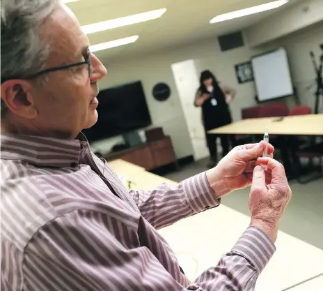  ?? MICHELLE BERG ?? Addictions expert Dr. Peter Butt demonstrat­es for reporters the Naloxone kits first responders carry to block the effects of the deadly opioid fentanyl. Paramedics used the life-saving medication to treat overdose victims four times in the city on the...