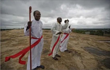  ?? THE ASSOCIATED PRESS ?? Pastors from the Apostolica­l Holy Church sing and pray for their country from the top of a large rock known locally as “God’s Footprint” on the outskirts of Harare, Zimbabwe, on Sunday.