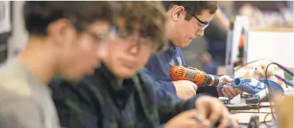  ??  ?? Matthew Peters, right, a 11th-grader at Northern Lehigh High School, takes a drill Thursday to a toy that needs to be modified. One of the items Peters helped modify was a movie tie-in toy called the ‘Despicable Me Fart Blaster.’