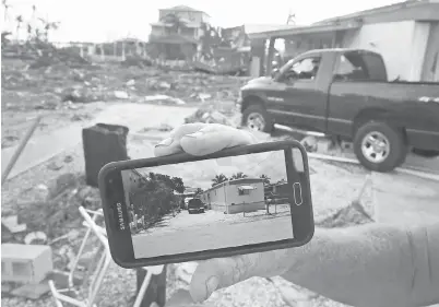  ?? — Gambar AFP ?? PENDUDUK Dan Weeks menunjukka­n gambar rumah bergerakny­a yang disimpan dalam telefon bimbitnya di hadapan lot yang kini kosong sebelum Irma memusnahka­nnya di Marathon, Florida kelmarin.