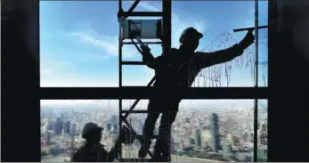  ?? YANG JIANZHENG / FOR CHINA DAILY ?? Workers clean a window at the Shanghai World Financial Center on Feb 9, just before Spring Festival.