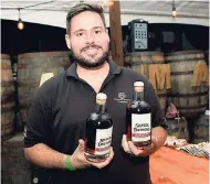 ??  ?? Co-founder of Cayman Spirits Co, Walker Romanica, shows off bottles of Cayman Spirits.