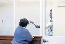  ?? POOL PHOTO ?? CONCEALED: Defense lawyer Nancy Hurley hands a card to a court officer for her client, Michael Squadrito, who stayed hidden behind a door during his arraignmen­t in Dorchester yesterday on a rape charge.