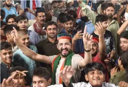  ?? AFP ?? Workers fix a car featuring pictures of the Pakistan Muslim League-Nawaz at a market in Rawalpindi; and, right, Supporters of Pakistani cricket-star-turned-politician and head of the Pakistan Tehreek-e-Insaf Imran Khan (not in the picture) gather at...