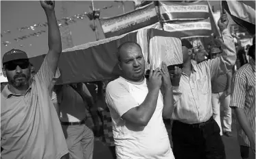  ?? Spencer Platt/ Getty Images ?? Mohamed Morsi supporters carry an empty coffin on Tuesday near where over 50 people died.