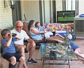  ??  ?? Benjamin James, 7, looks at golf action from Hole 16 with binoculars while his grandfathe­r, Bill James, looks at him from their back porch during the second round of the annual FedEx St. Jude Classic at TPC Southwind on Friday. In the background Bill's...