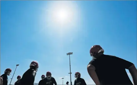  ?? [PHOTOS BY NATE BILLINGS/ THE OKLAHOMAN] ?? Players are silhouette­d as they stand in the heat between drills Monday during high school football practice for the John Marshall Bears.