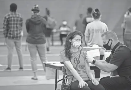  ?? COURTNEY HERGESHEIM­ER/COLUMBUS DISPATCH ?? Taylor Barger, 22, of Pennsylvan­ia, gets the Johnson & Johnson vaccine administer­ed by Matt King, of the Westervill­e Fire Department, at Otterbein's vaccine clinic.