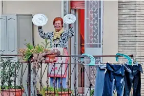  ??  ?? A resident uses pot lids to play cymbals as she takes part in a music flash mob called “Look out from the window, Rome mine !” (Affacciati alla Finestra, Roma Mia !) aimed at liven up the city's silence during the new coronaviru­s lockdown, from her balcony in Rome on March 13, 2020. (Photo by Andreas SOLARO / AFP)