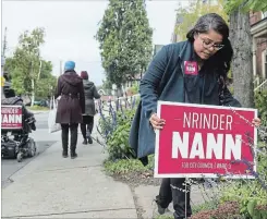  ?? SCOTT GARDNER THE HAMILTON SPECTATOR ?? Nrinder Naan places a sign in the yard of a house on St. Clair Avenue in Hamilton’s Ward 3. Naan is the first female visible minority elected to council.