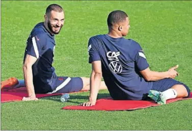  ??  ?? Benzema y Mbappé, estirando los cuádriceps en un entrenamie­nto con la selección francesa.