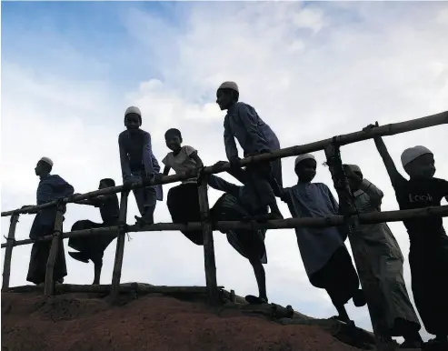  ?? DIBYANGSHU SARKAR / AFP / GETTY IMAGES ?? Young Rohingya refugees gather next to a bamboo railing while looking at a road below at Kutupalong refugee camp in Bangladesh on Wednesday.