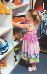  ??  ?? Sadie Hawk, age 2, enjoys a few moments of play while her brother Abe watches his mother Misty Hawk check merchandis­e at Helping Hands Thrift Store in Rockmart.