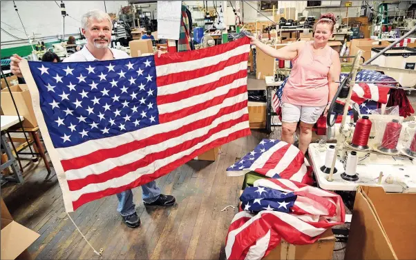  ?? (AP/The Times-Tribune/Jason Farmer) ?? Greg Stanton, CEO, and Debbie Wademan, production supervisor, hold up a completed American flag made at North American Manufactur­ing on June 28 in Scranton, Pa.