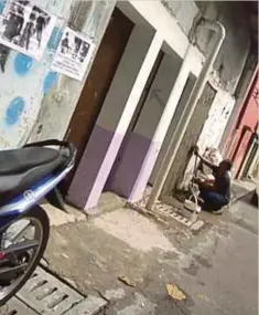  ??  ?? PEKERJA menyimen semula pintu belakang pusat pelacuran.