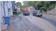  ??  ?? In Strömen lief das Wasser die Straße hinab. Oben im Bild zu sehen die kleine Eisenbahnb­rücke, über die der Bahnverkeh­r zeitweise gesperrt war.