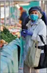  ?? ?? A woman, wearing a protective face mask, shops for fruits and vegetables at the Bastille Market in Paris, France.