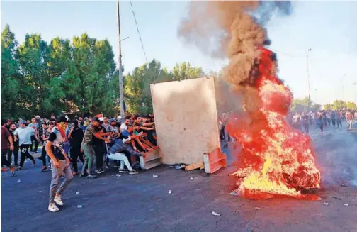  ?? Associated Press ?? Anti-government protesters set fire and close a street during a demonstrat­ion in Baghdad on Friday.