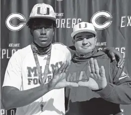  ?? SAM NAVARRO For the Miami Herald ?? Jabari Ishmael, left and Ryan Rodriguez, do the ‘U’ sign after signing National Letters of Intent committing to join the University of Miami football program during a ceremony at Christophe­r Columbus High School on early signing day on Wednesday.