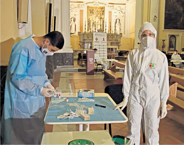  ??  ?? Healthcare workers carry out swab tests in the Basilica di San Severo in Naples. The south of Italy has been hit badly by the second Covid-19 wave. A hospital staff member in Palermo, Sicily, right, decontamin­ates herself after a shift