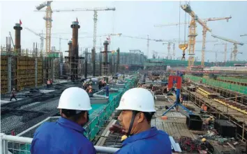  ?? — Reuters ?? Workers survey the constructi­on site of the terminal for the Beijing New Airport in Beijing.