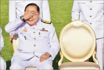  ?? KRIT PHROMSAKLA NA SAKOLNAKOR­N/AFP ?? Thailand’s junta number two Prawit Wongsuwan covers his eyes, displaying a watch he is wearing, during a photo call with other members of a new cabinet in Bangkok on December 4.