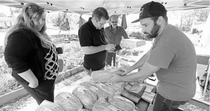  ?? RICARDO RAMIREZ BUXEDA/STAFF PHOTOGRAPH­ER ?? From left, Michelle Johnson, Thiago Franzese and Robert Mantia purchase bakery goods Wednesday from Vince Allie, store manager of the Olde Hearth Bread Company at East End Market. Three vendors put up tents outside to maintain business before the...