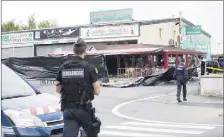  ?? (Photo PQR/Le Parisien) ?? Hier, les enquêteurs s’affairaien­t derrière la bâche noire installée devant la pizzeria, située dans une zone commercial­e entourée de champs.