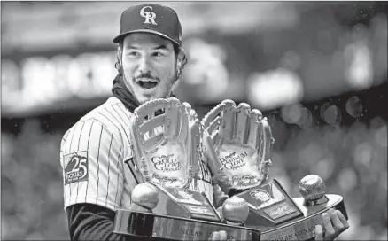  ?? Matthew Stockman Getty Images ?? NOLAN ARENADO receives at the Colorado Rockies home opener Friday the Gold Glove Award for National League third basemen for the 2017 season and the Platinum Glove Award for best overall fielder in the league. Arenado has won five Gold Gloves in a row.