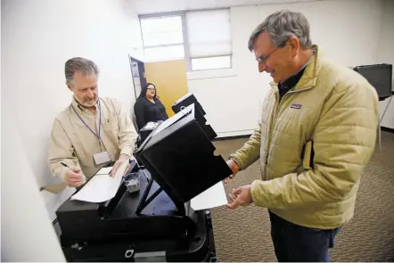  ?? LUIS SÁNCHEZ SATURNO/THE NEW MEXICAN ?? Poll worker Michael J. Browne, left, helps voter Robert Darmitzel cast his early voting ballot Wednesday at City Hall. For the first time, Santa Fe voters may cast ballots using a ranked-choice system for the mayoral candidates.