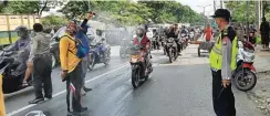  ?? GALIH ADI PRASETYO/JAWA POS ?? STERILISAS­I: Petugas menyemprot­kan cairan disinfekta­n kepada pengendara di persimpang­an Kedung Cowek kemarin.