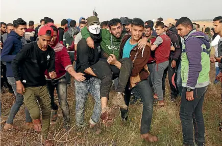  ?? PHOTOS: AP ?? Palestinia­n protesters evacuate a wounded youth during clashes with Israeli troops along Gaza’s border with Israel.