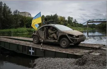  ?? AP ?? MASS GRAVES: Ukrainian paratroope­rs drive a vehicle with the Ukrainian flag on the bridge across Siverskiy-Donets River in the recently retaken area of Izium, Ukraine.