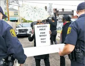  ?? Pam Panchak/Post-Gazette ?? Homewood resident Sandra Xandirani King continues to shout her protest over the groundbrea­king for the Kelly Hamilton housing project in Homewood while Pittsburgh police move a barrier and the protesters farther from the event Thursday.