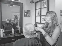  ?? JIM DAY/THE GUARDIAN ?? Coralee Schneider cuts Stan MacPhee's hair Friday at the Downtown Barber Shop in Charlottet­own. Barbers and hairstylis­ts on P.E.I. dealt with a steady stream of customers on their first day back in business since a mandatory shut-down in mid-March due to the pandemic.