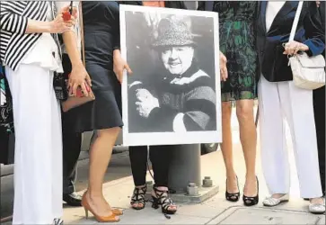  ?? Photog raphs by Christina House For The Times ?? MICKEY ROONEY’S daughter holds his portrait during the dedication of Mickey Rooney Memorial Square on Sunset Boulevard and Orange Drive. The site is near Hollywood High School, which the late actor attended.