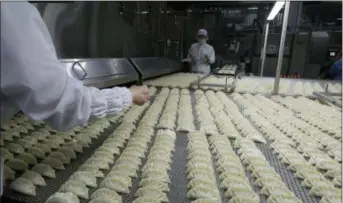  ?? AP PHOTOS/LEE JIN-MAN ?? Workers inspect dumplings on a conveyor belt that are made at an automated factory of CJ CheilJedan­g Corp. in Incheon, South Korea. South Korea’s largest food company is making a multimilli­on-dollar bet on “mandu,” developing its own machines to automate the normally labor-intensive production of the Korean dumpling and building factories around the world.