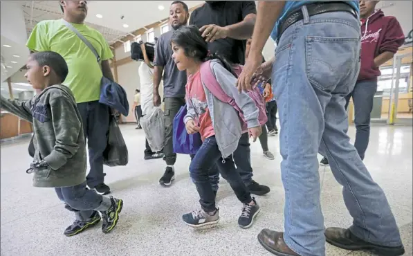  ?? Eric Gay/Associated Press ?? A group of immigrants from Honduras and Guatemala seeking asylum arrive at a bus station after they were processed and released by U.S. Customs and Border Protection on Thursday in McAllen, Texas, a day after President Donald Trump signed an executive...