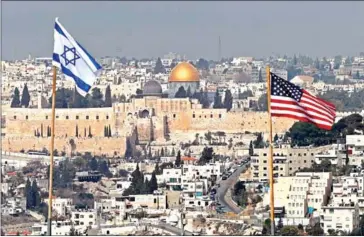  ?? AHMAD GHARABLI/AFP ?? The Israeli and US flags on the roof of an Israeli settlement building in East Jerusalem and Jerusalem’s Old City with the Dome of the Rock mosque in the centre, on December 13.