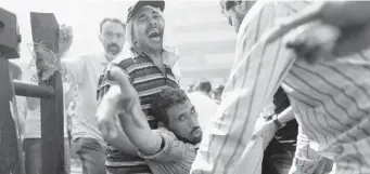  ?? HASSAN AMMAR/THE Associated Press ?? Supporters of Egypt’s ousted president Mohammed Morsi evacuate a wounded man during clashes in
Ramses Square in Cairo on Friday. At least 82 people were killed during the day’s violence.