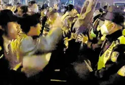  ?? —AFP ?? FACE OFF This video grab made available on Sunday shows demonstrat­ors pumping fists and shouting slogans against COVID curbs as police hold their ground in Shanghai.