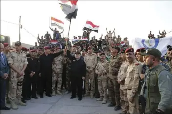  ??  ?? Iraq’s prime minister Haider al-Abadi raises the national flag as he addresses forces from a small base on the edge of Mosul’s Old City, where heavy clashes have been underway for days on Monday. Al-Abadi returned to Mosul and declared victory against...