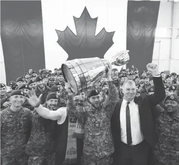  ?? JONATHAN HAYWARD / THE CANADIAN PRESS ?? Cpl. Cody Williamson of Smithers, B.C., hoists the Grey Cup as CFL commission­er Randy Ambrosie joins the celebratio­n during the Cup’s arrival at Canadian Forces Base Edmonton on Tuesday.
