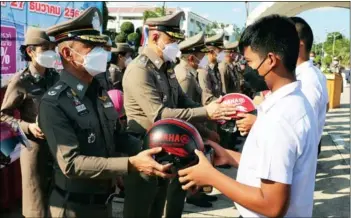  ?? Photo: PR Phuket ?? A student receives a helmet from Region 8 Police at a ‘Wear a helmet 100%’ campaign event on Monday (Dec 27).