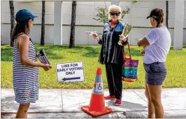  ?? DAMON HIGGINS / THE PALM BEACH POST ?? Susan Keselman of West Palm Beach (center) speaks with volunteer Christine Clawson (right) before heading inside the Palm Beach County Supervisor of Elections office to cast an early vote Monday in the state’s primary.