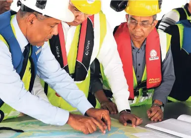  ?? PHOTOS BY CHRISTOPHE­R SERJU ?? Professor Gordon Shirley (left), president and chief executive officer of the Port Authority of Jamaica, highlighti­ng details on a map of the dredging operation to Prime Minister Andrew Holness (centre) and Dr Horace Change, minister without portfolio in the Ministry of Job Creation and Growth. The men were aboard the cutter suction dredger operating in Gordon Cay during yesterday’s tour of the developmen­t work underway at Kingston Freeport Terminal.