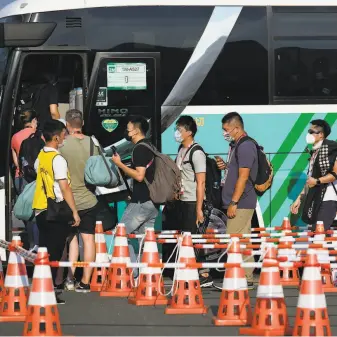  ?? Markus Schreiber / Associated Press ?? A maze of cones lead people onto a bus at the main transport hub at the Olympics in Tokyo. Getting to and from events is often a confusing endeavor.