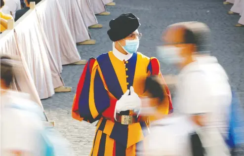  ?? REMO CASILLI / REUTERS ?? A Swiss Guard wearing a protective face mask patrols ahead of Pope Francis's weekly general audience at the Vatican in September.